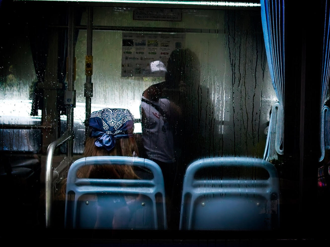 Passenger seen through a rain-covered bus window in Bangkok, Thailand.